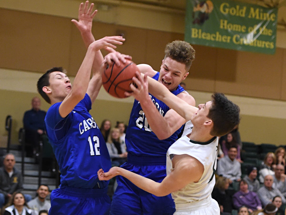 Carson's Tez Allen grabs a rebound between teammate Trenten Robison, left, and Manogue's Aidan Cantwell during the first half of Tuesday's game at Bishop Manogue.