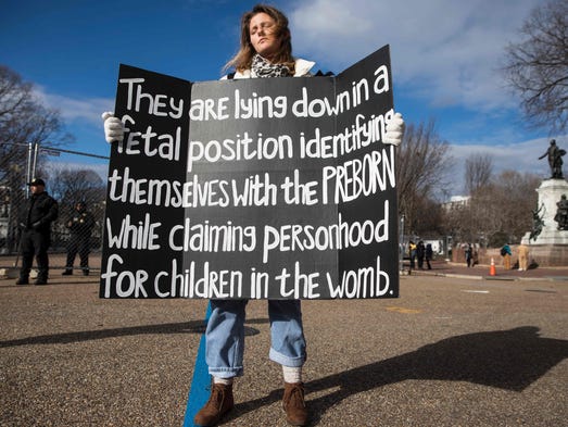 A demonstrator holds a sign during a "die-in" in front