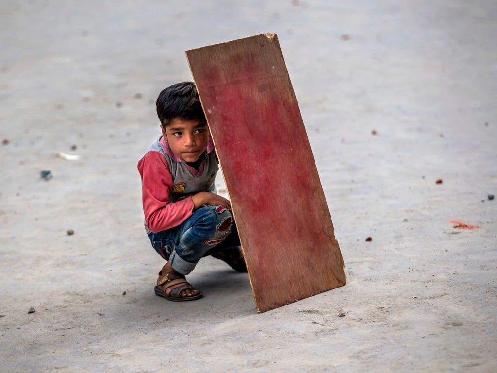 A Kashmiri boy shields himself with plywood from stones and glass marbles during a clash between Indian police and protesters in Srinagar, India.