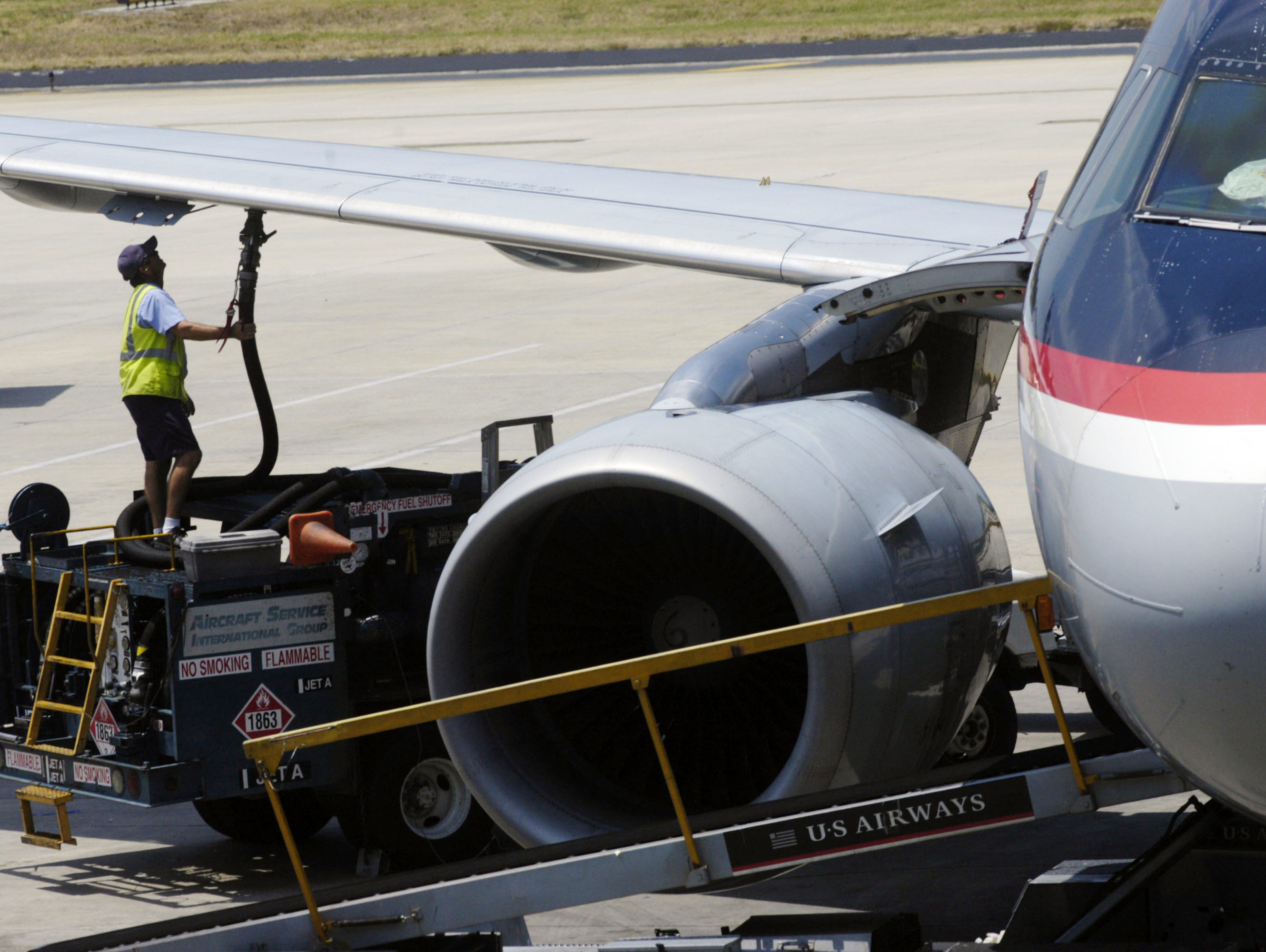 A worker hooks up a fuel hose to an airplane at Tampa International Airport.