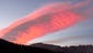 A massive cloud glows pink at sunset above Mitre Basin,
