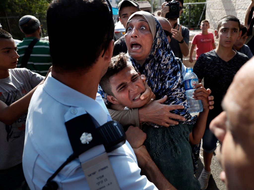 A Palestinian woman holds on to her son as an Israeli policeman detains him during a protest in front of a Palestinian house whose occupants were evicted Sept. 5 in East Jerusalem. The Shamasnehs, including 84-year-old grandfather Ayoub, were evicted