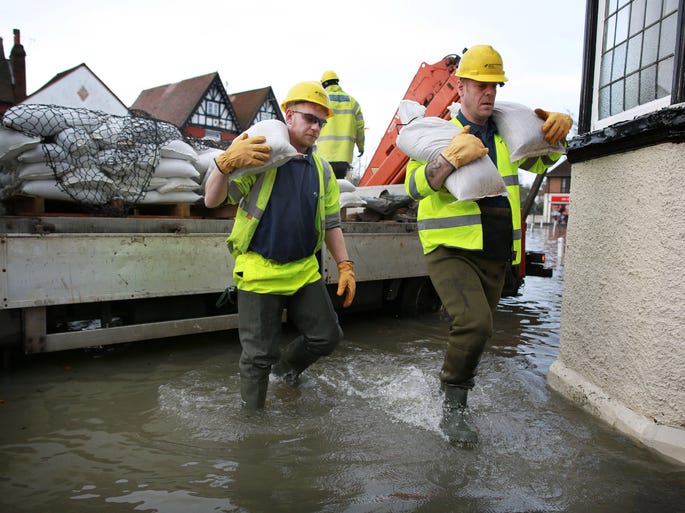 Electricity workers unload sandbags to protect a sub station as floodwater continues to rise from the river Thames in Datchet.