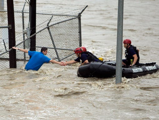 Rescue personnel grab the the hand of a man stranded