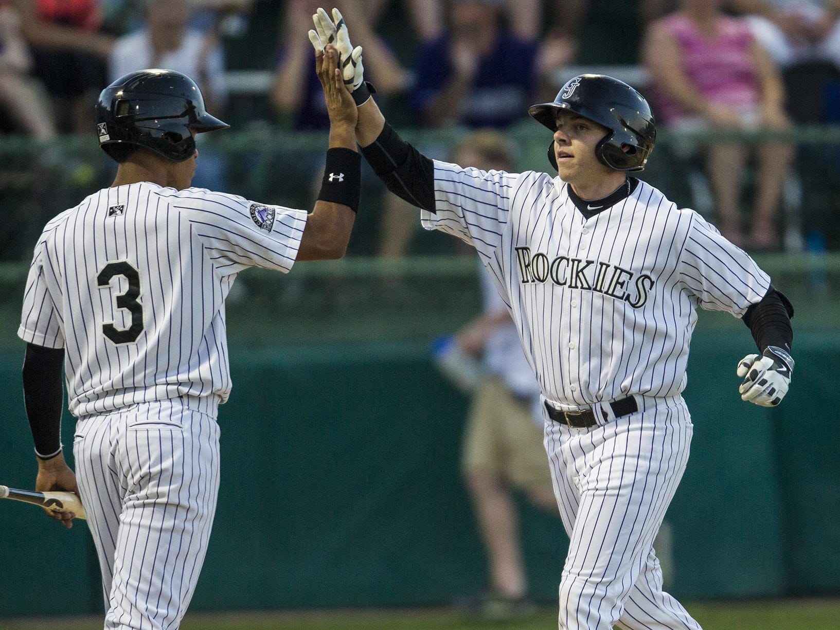 Rocky Mountain High School grad Cole Anderson, right, celebrates his first career hit, a home run, during the Grand Junction Rockies home opener Monday.