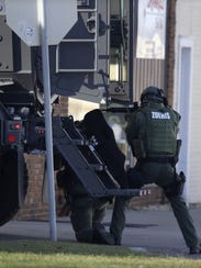 Police officers use an armored truck for cover during