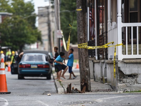 Kids play under the caution tape near a utility pole