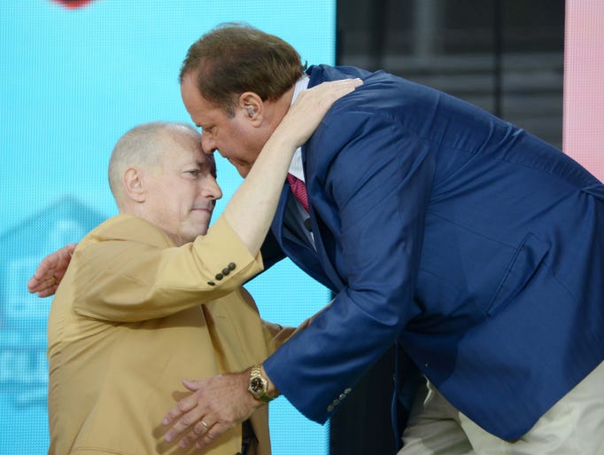 Jim Kelly (left) and Chris Berman embrace at the 2014 Pro Football Hall of Fame Enshrinement at Fawcett Stadium.