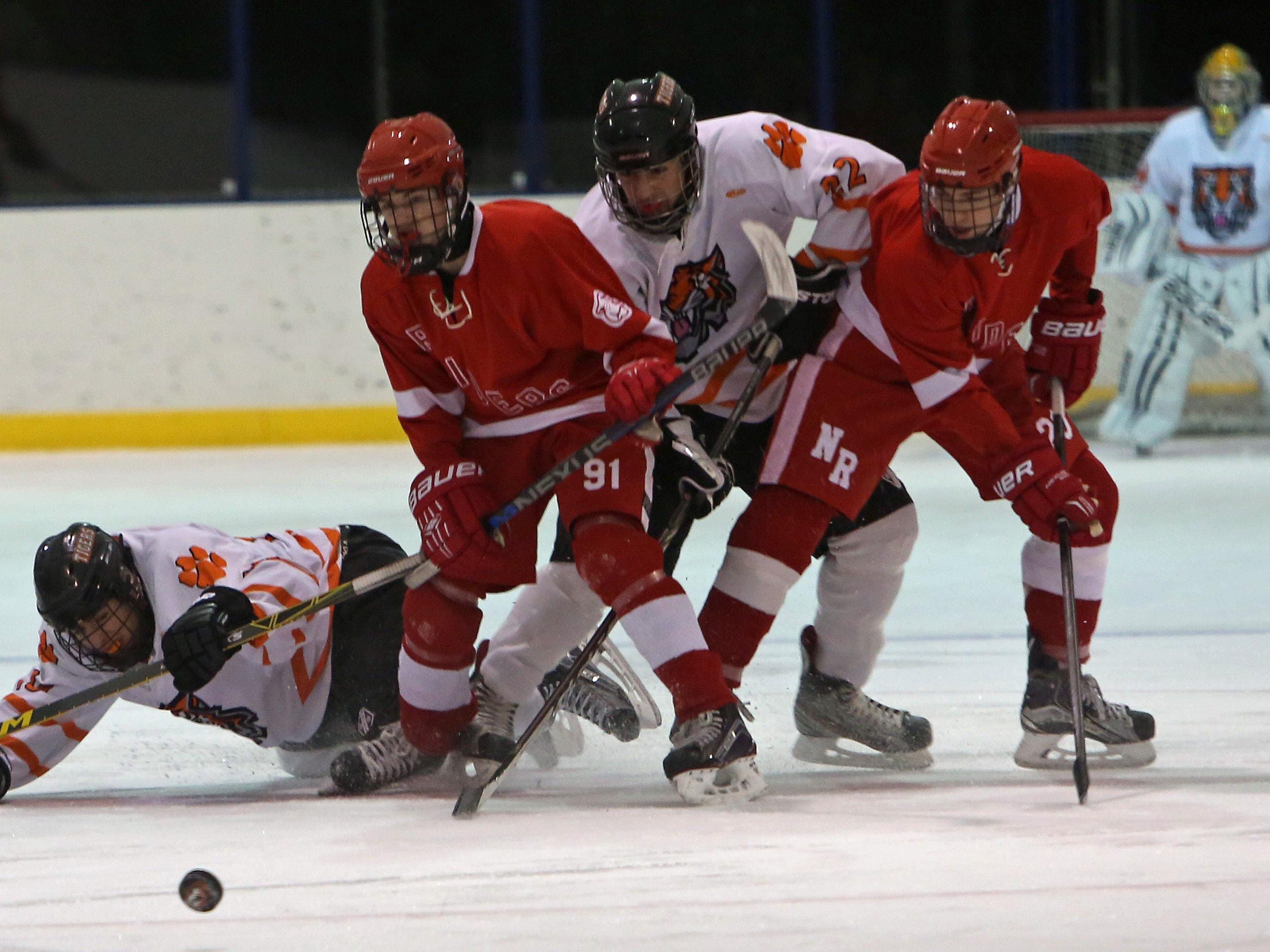 White Plains’ Harry Seymour, left, and Chris Schiavone, second from left, battle for the puck with North Rockland’s Chris Hilliard (91) during their game at Ebersole Ice Rink in White Plains Thursday. The game ended in a 4-4 tie.