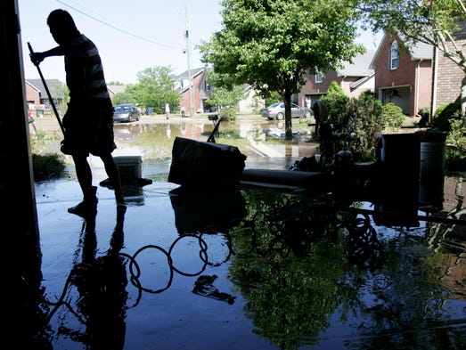 Vu Nguyen cleans mud out of his garage after his home