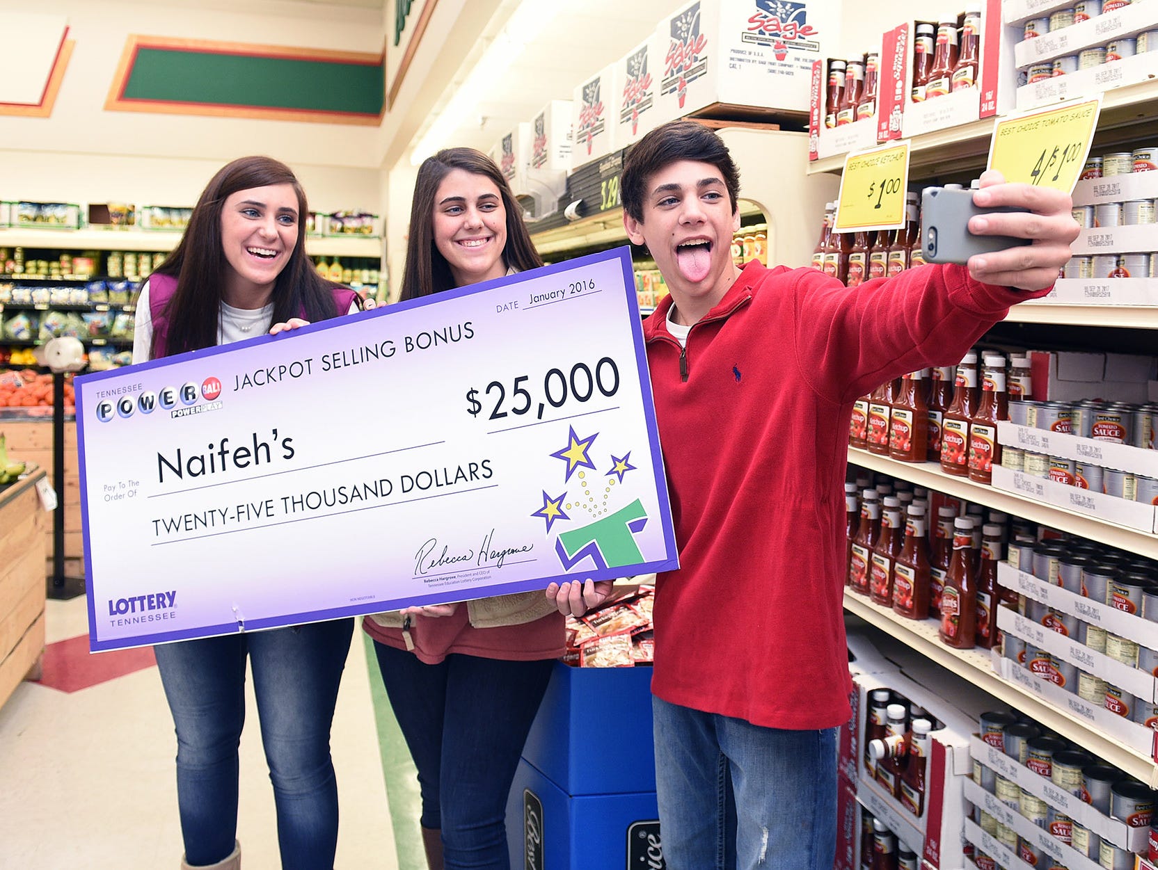 Ally, Abby and Oney Naifeh take a selfie with their family's Tennessee lottery check that was presented at their family's store, Naifeh's Food Mart, on Thursday Jan. 14, 2016, in Munford, Tenn. The store received the money for selling one of the thre