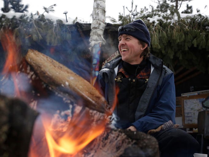 Tom Lakenen greets snowmobilers as he keeps a fire
