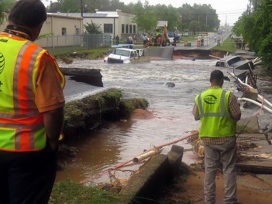 Officials look over the damage caused by the washout of Old Corry Field Road Wednesday in Pensacola, Fla.