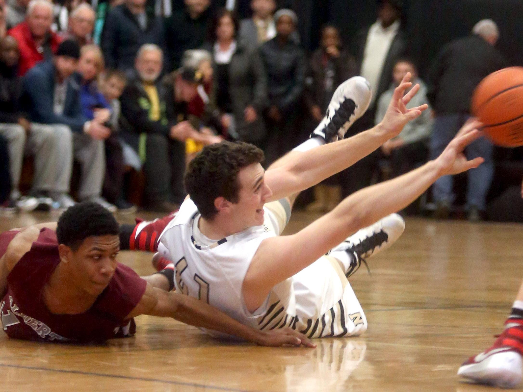Nanuet’s Aedan Lombardo passes the ball while scrambling on the floor with Justin Bullock of Albertus Magnus during Wednesday’s game.