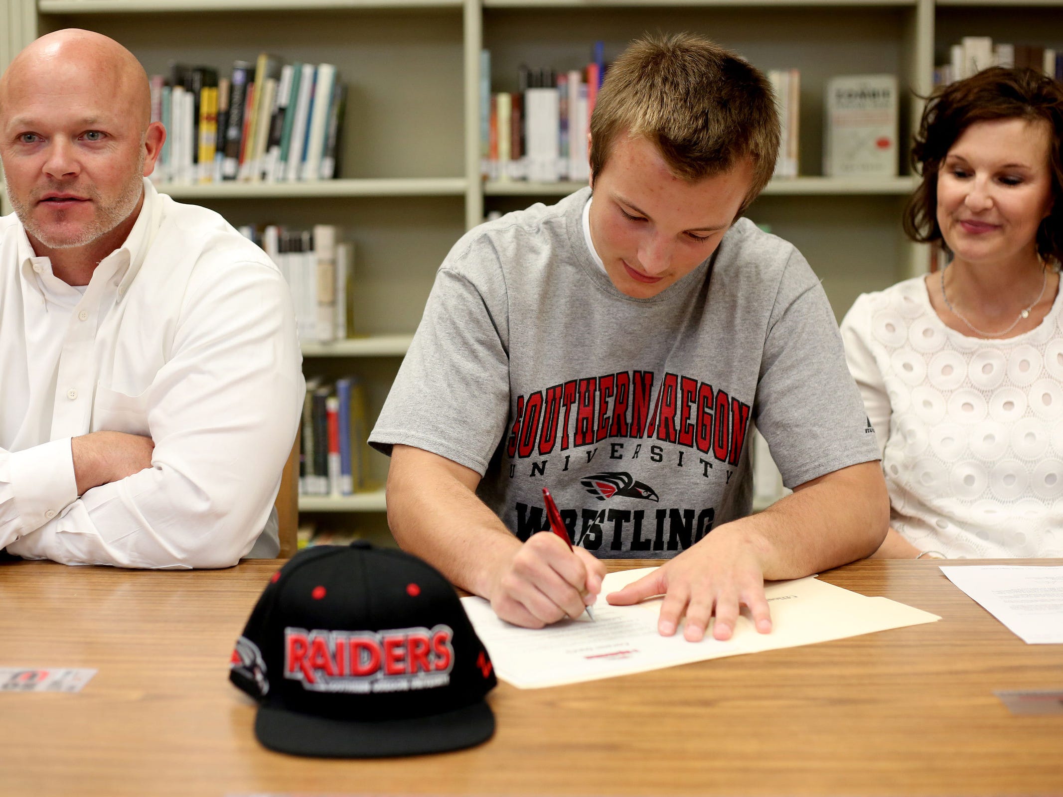 Corson Davis signs a letter of intent to wrestle at Southern Oregon. Davis is sitting between his parents, Brett and Catherine Davis, during a signing day ceremony Monday, May 18, at Sprague High School.