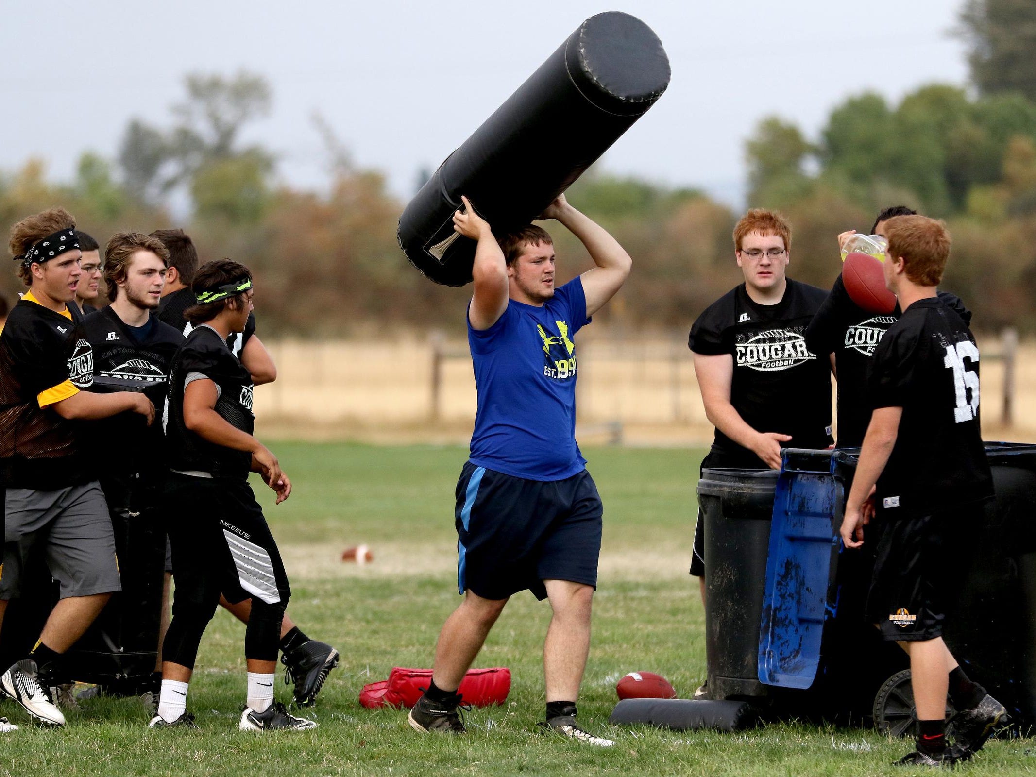 Players move equipment during football practice at Cascade High School in Turner, Ore., on Friday, Aug. 14, 2015.