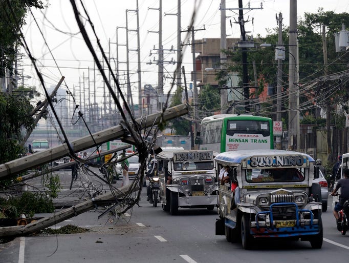 Vehicles squeeze past toppled power poles in Muntinlupa.