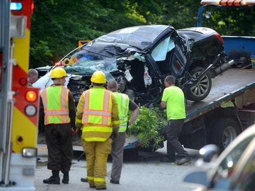 Workers secure a car involved in a fatal crash on the