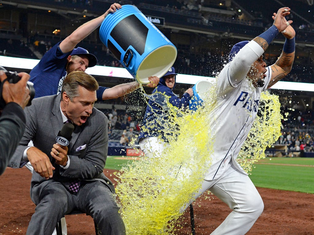 The San Diego Padres' Hector Sanchez (right) is doused by relief pitcher Ryan Buchter (background, right) and relief pitcher Brandon Maurer (background left) next to FOX Sports sideline analyst Bob Scanlan after the Padres beat the Detroit Tigers 7-3