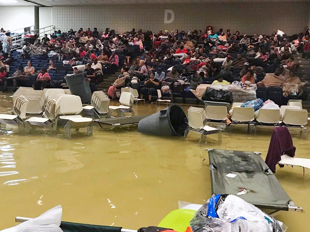 In this photo provided by Beulah Johnson, evacuees sit in the bleachers at the Bowers Civic Center in Port Arthur, Texas on Aug. 30, 2017, after floodwaters caused by Tropical Storm Harvey inundated the facility overnight. Authorities said it's not c
