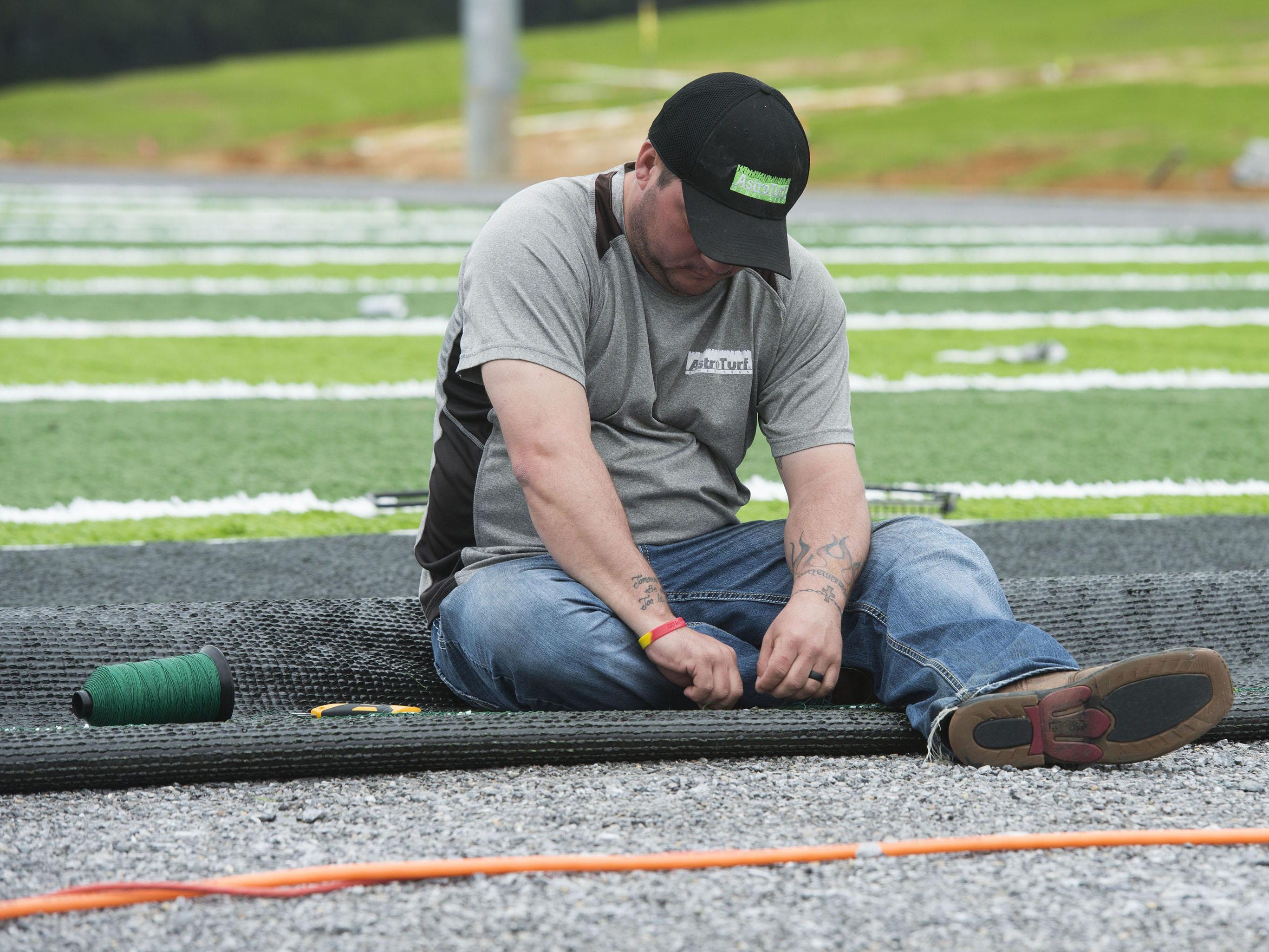 Corey King, left, and Conner Whitener, right, uses an air driven sewing machine to stitch together sections of AstroTurf during the installation of the new playing surface at University of West Football facility Friday morning Jan. 8, 2016.