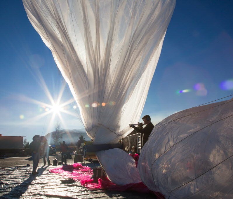 Project Loon team member Bill Rogers fills a balloon with helium while Paul Acosta monitors inflation in this 2013 file photo.