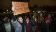 Protesters hold up signs and yell during a protest