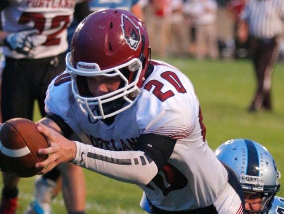 Portland's Gabe Schrauben, top, dives over the goal line for a touchdown against Lansing Catholic's Nic Baker (5), and Ben Rashid Friday, Sept. 18, 2015, in Holt, Mich.