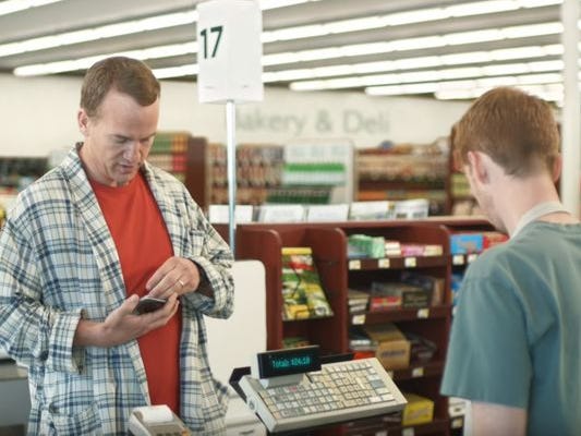 Peyton Manning, left, tries to find a coupon for an item he's buying in a DirecTV commercial. The grocery clerk, right, is Nashville native and Trevecca graduate James Austin Johnson.