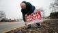 Bob Hill sets up signs along North Iowa Street in Dodgeville,