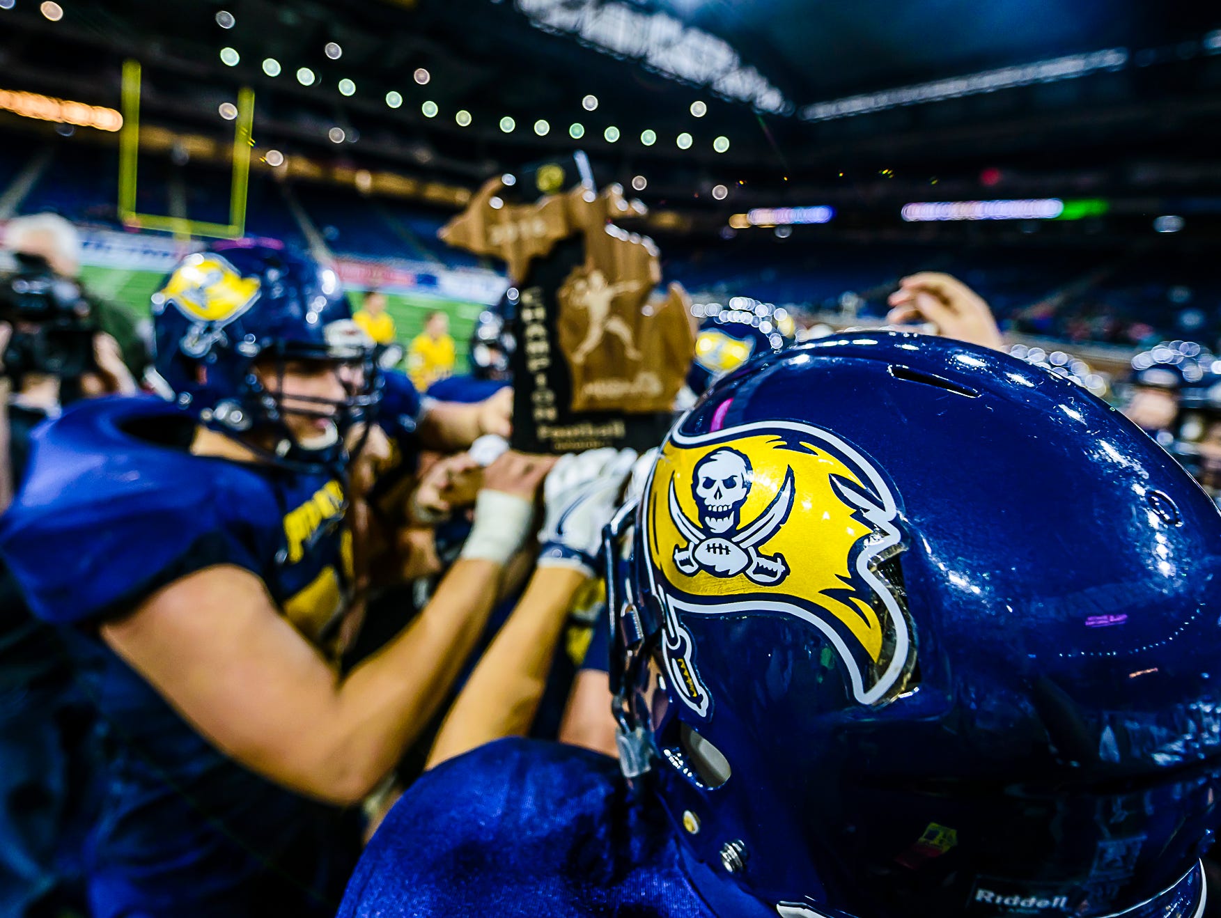 The Pewamo-Westphalia football team holds the Division 7 state championship trophy after defeating Detroit Loyola Saturday November 26, 2016 at Ford Field in Detroit.
