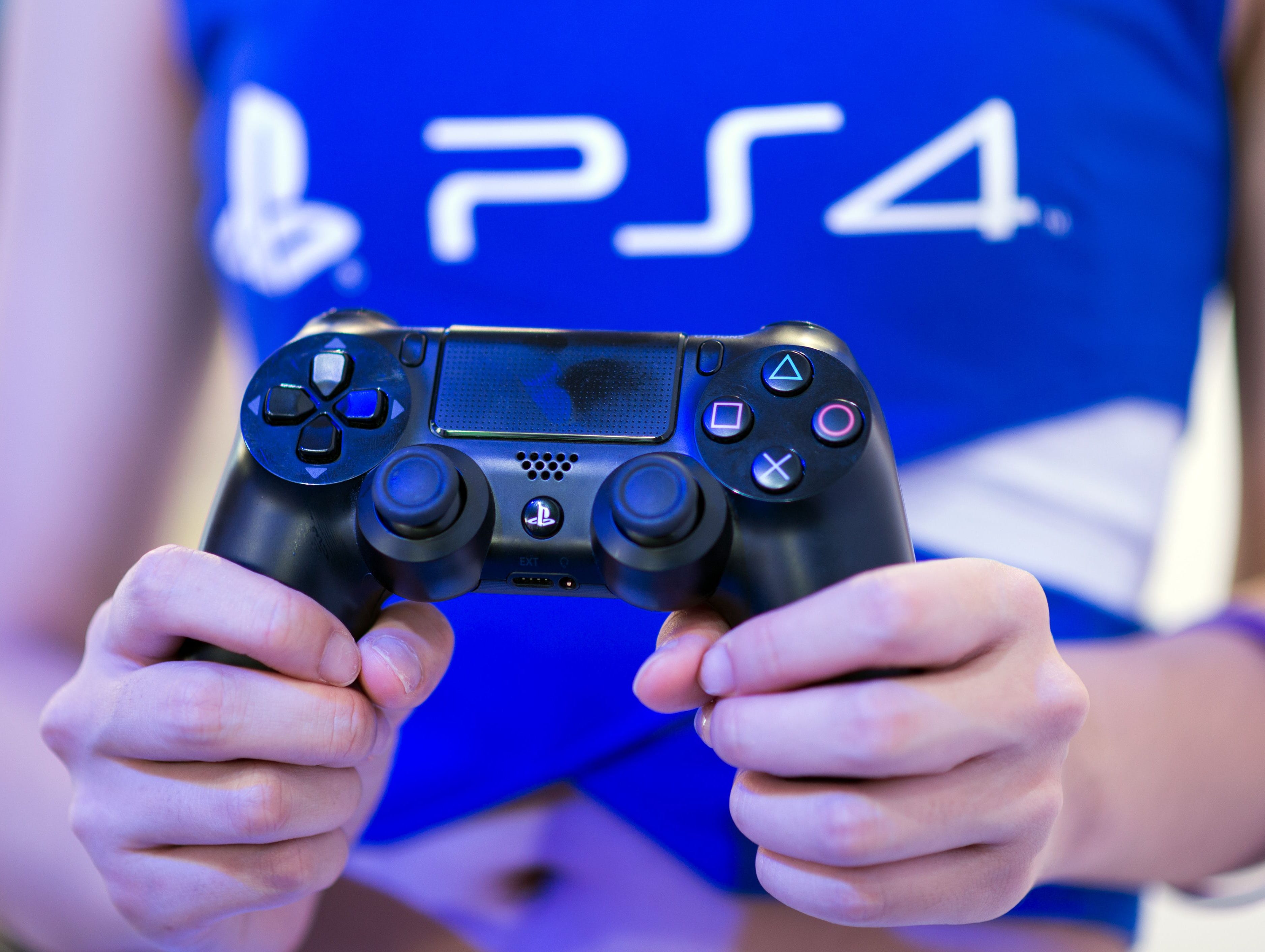 A hostess holds a remote of a  Playstation 4 at the Sony booth during the China Joy fair in Shanghai on July 31, 2014. The gamer fair China Joy (China Digital Entertainment Expo & Conference) opens its doors from July 31 to August 3, 2014. Sony said 