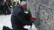 A holocaust survivor places flowers in commemoration