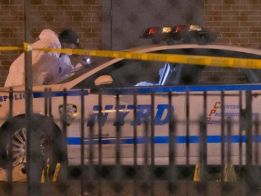 Investigators work at the scene where two NYPD officers