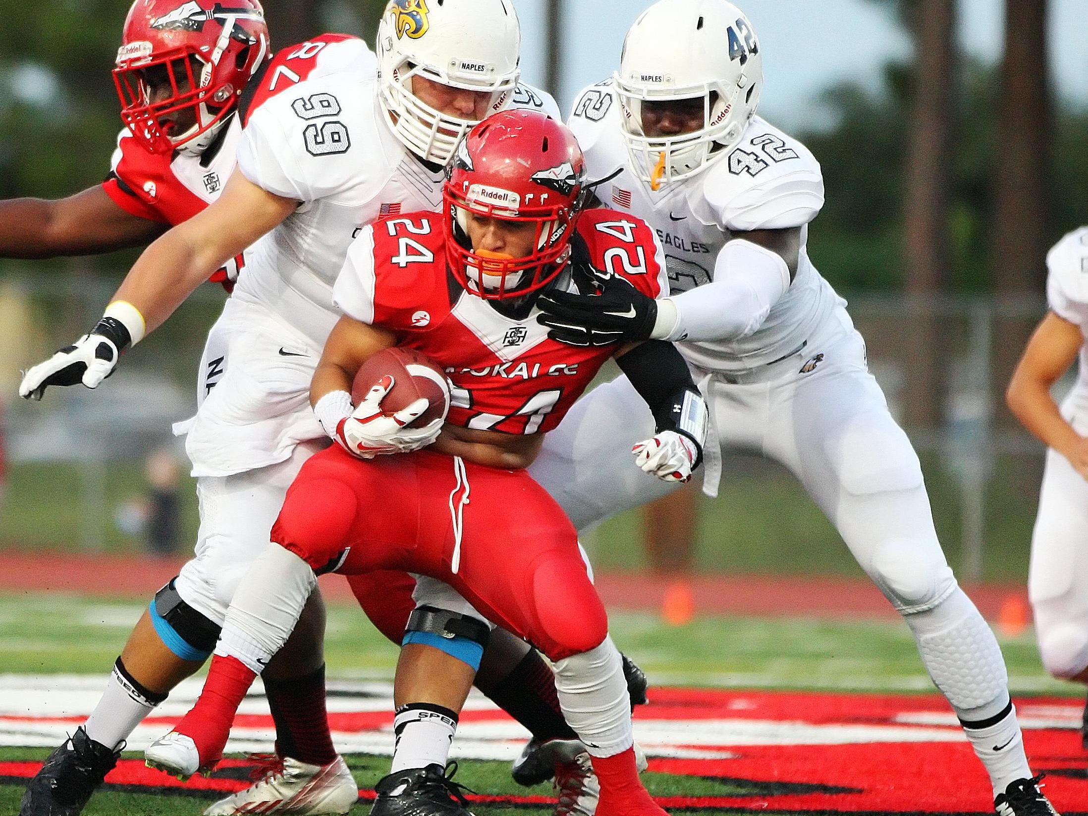 Naples High School defenders Crandall Maines, left, and Wycleff Phanor tackle Immokalee's John Garza on Friday at Immokalee High School. Naples beat Immokalee 63-7.