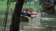 Two boys float in an old wooden box in an area of the