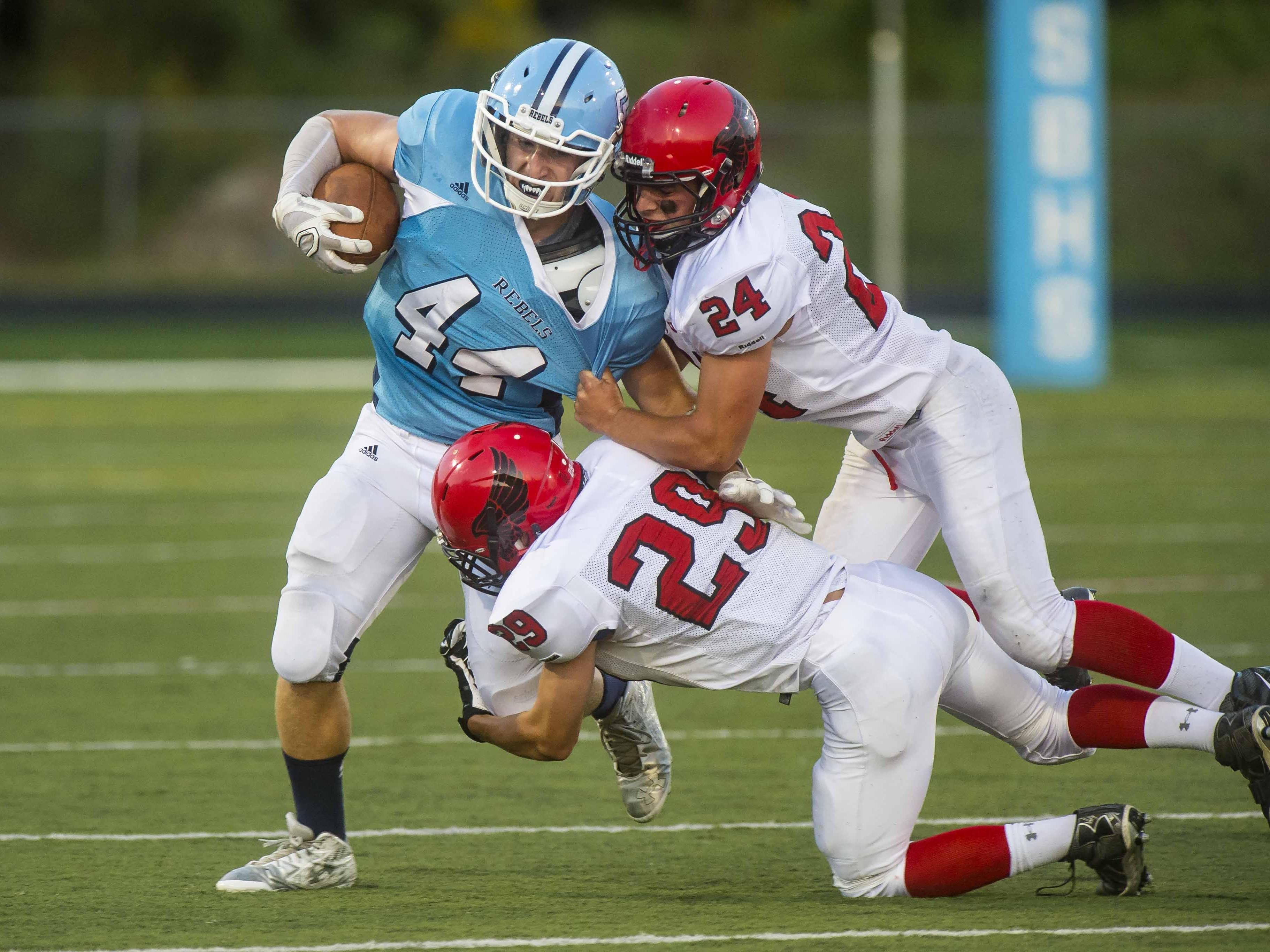 South Burlington's Jeremy Clements, left, is tackled by Champlain Valley’s Nick Kinneston, top, and Braven Bose in South Burlington on Friday night.