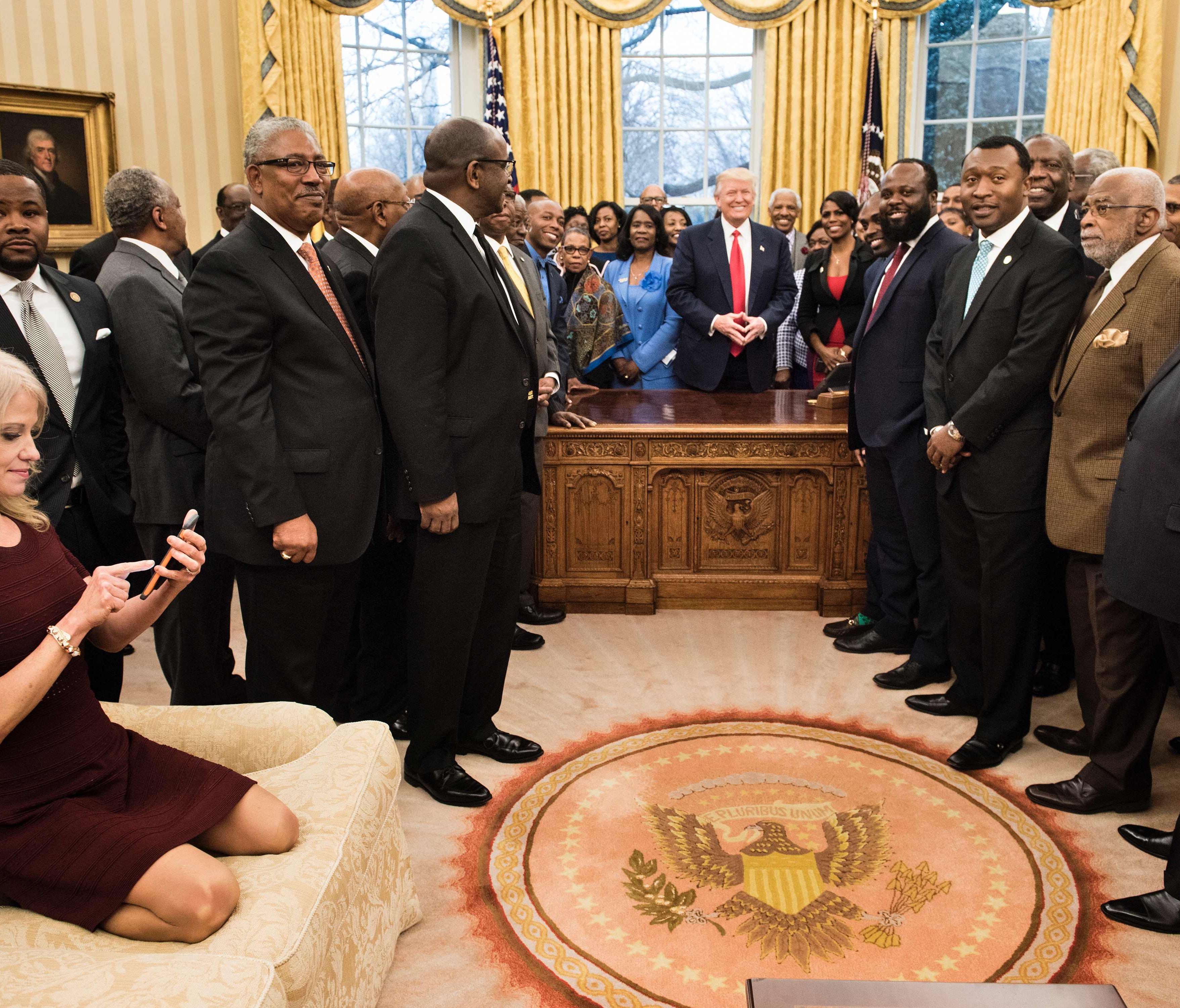 Kellyanne Conway is pictured kneeling on the Oval Office couch during President Trump's meeting with leaders from historically black colleges and universities at the White House on Monday.