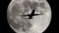 A passenger airliner crosses the full moon, also known