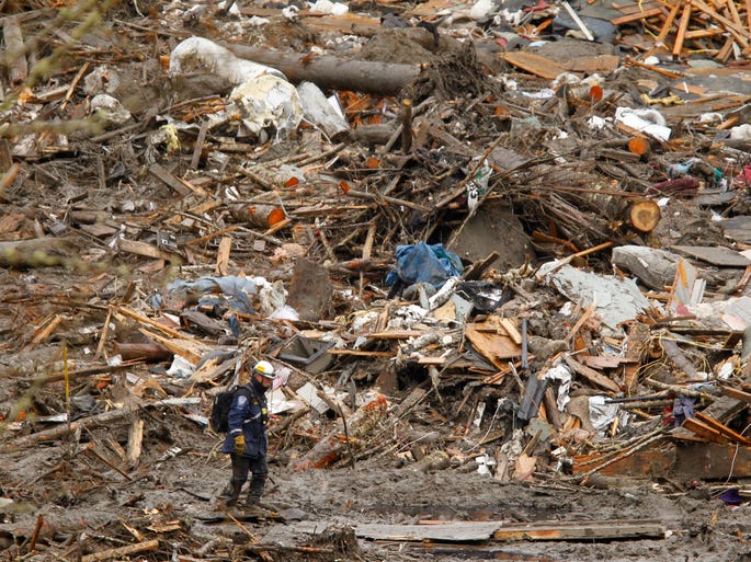 A searcher passes a massive pile of debris at the scene of a deadly mudslide in Oso, Wash., which struck the area March 22.