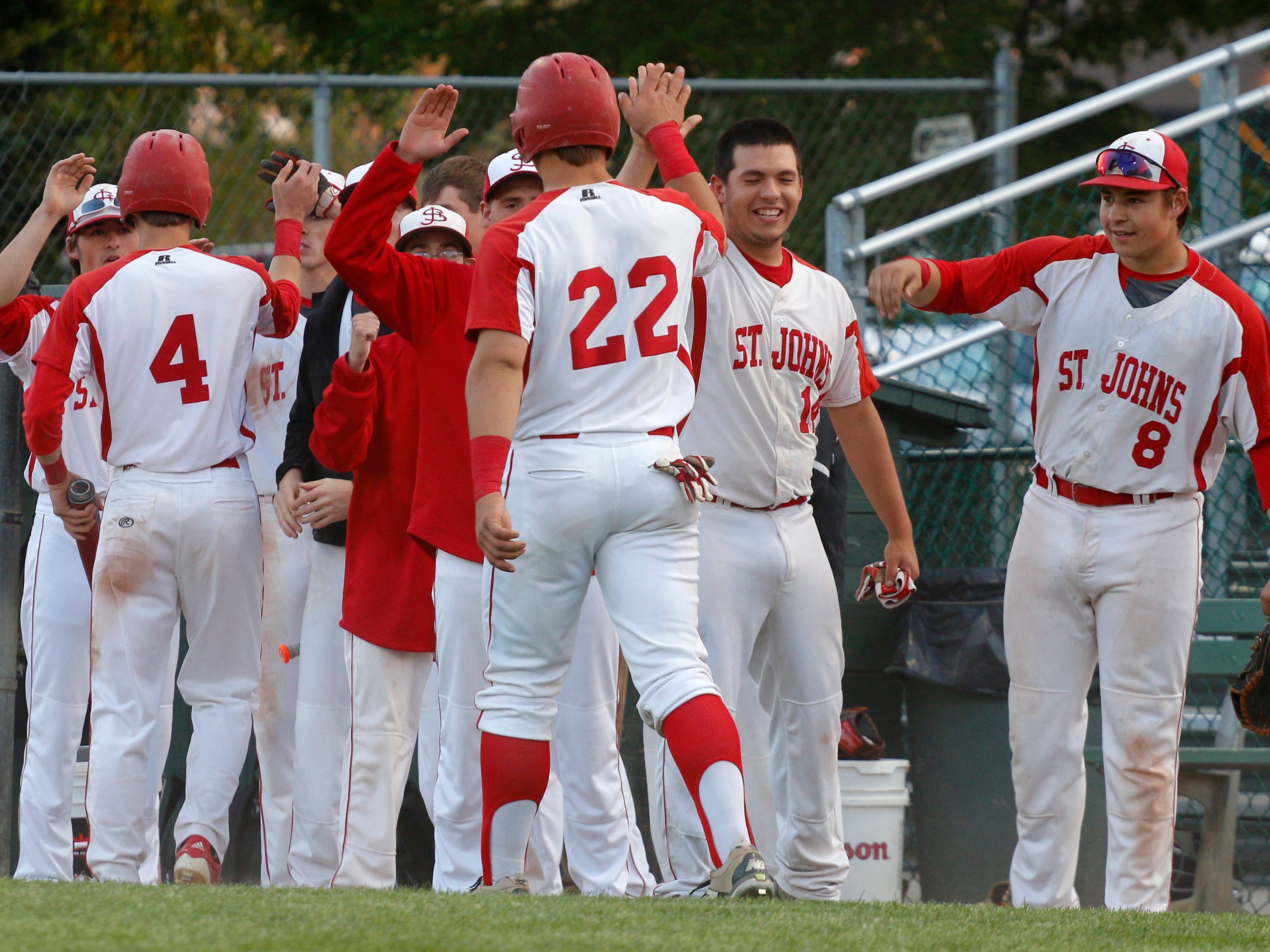 St. Johns' Alex Hudak (4) and Adam Proctor (22) are congratulated after scoring against Haslett during their Diamond Classic game Thursday, May 21, 2015, in Lansing, Mich.