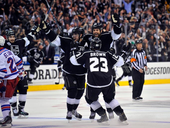 Los Angeles, CA, USA; Los Angeles Kings right wing Dustin Brown (23) celebrates with defenseman Willie Mitchell (right) and center Anze Kopitar (11) after scoring the game-winning goal in the second overtime period.