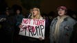 Protesters hold up signs and yell during a protest
