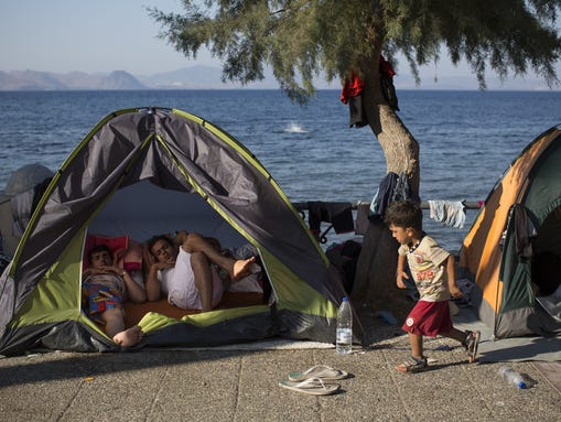 Migrant families sleep on the sea front in tents on
