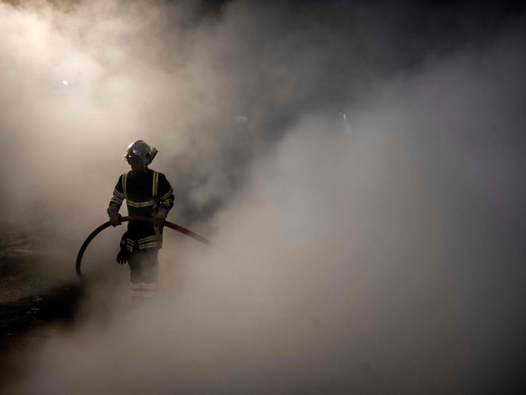 A firefighter extinguishes a fire set by prison guards demonstrating in front of Villefranche-sur-Saone prison in France.