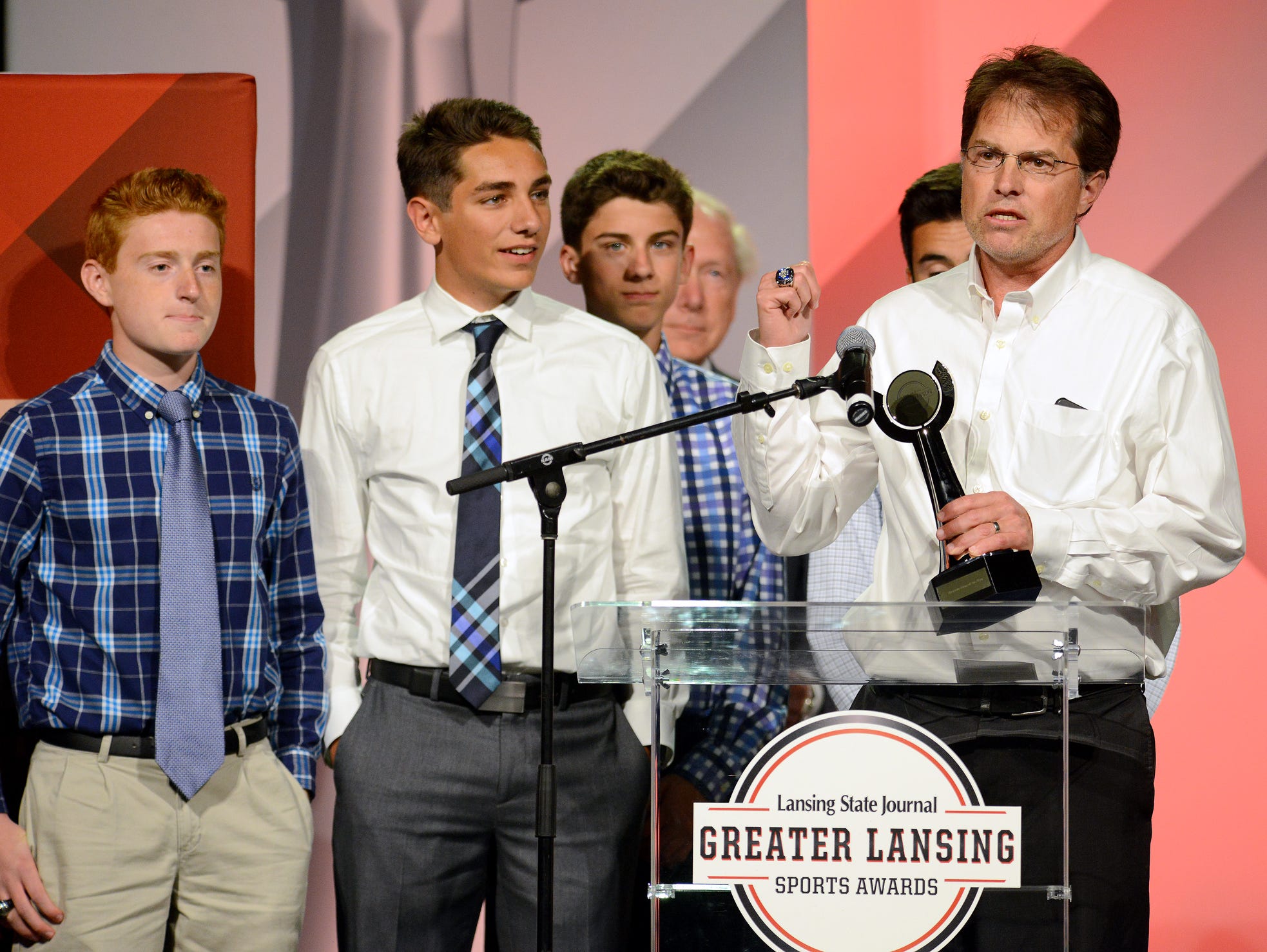 Lansing Catholic Cross Country coach Tim Simpson motions to members of the boys team behind him as he accepts the award for Team of the Year at the Lansing State Journal's Greater Lansing Sports Awards Show show Tuesday, June 7, 2016 at the Lansing Center.