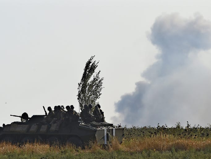 Soldiers on a Ukrainian army vehicle drive through a field as pro-Russia separatists shell an area.