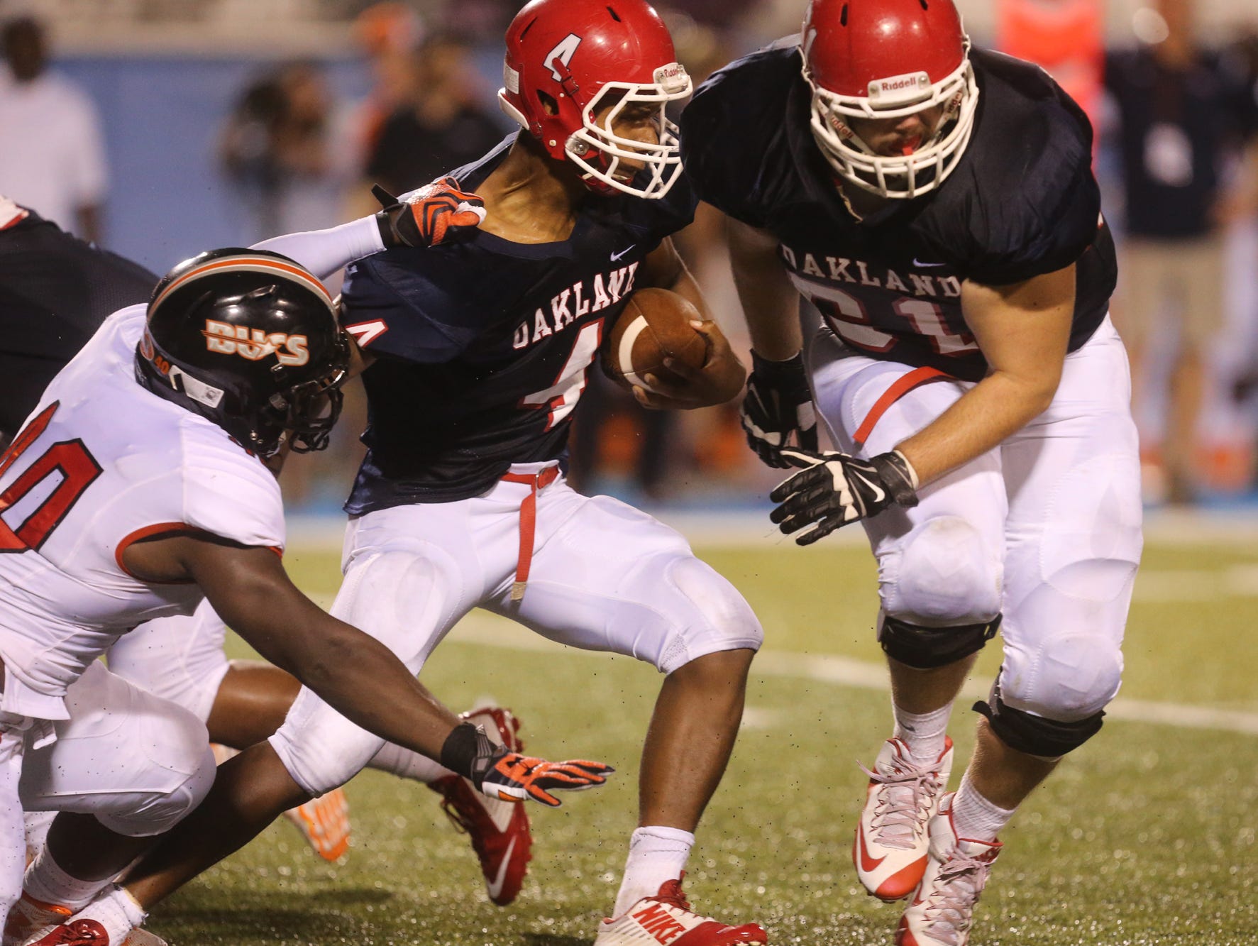 Oakland's Lazarius Patterson runs the ball as teammate Jacob Lowery tries to clear the way and Hoover's Christon Taylor tries to bring Patterson down during the second game at the Middle Tennessee Classic at MTSU's Floyd Stadium Saturday, Aug. 22, 2015.
