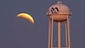 A lunar eclipse appears behind a hospital's water tower