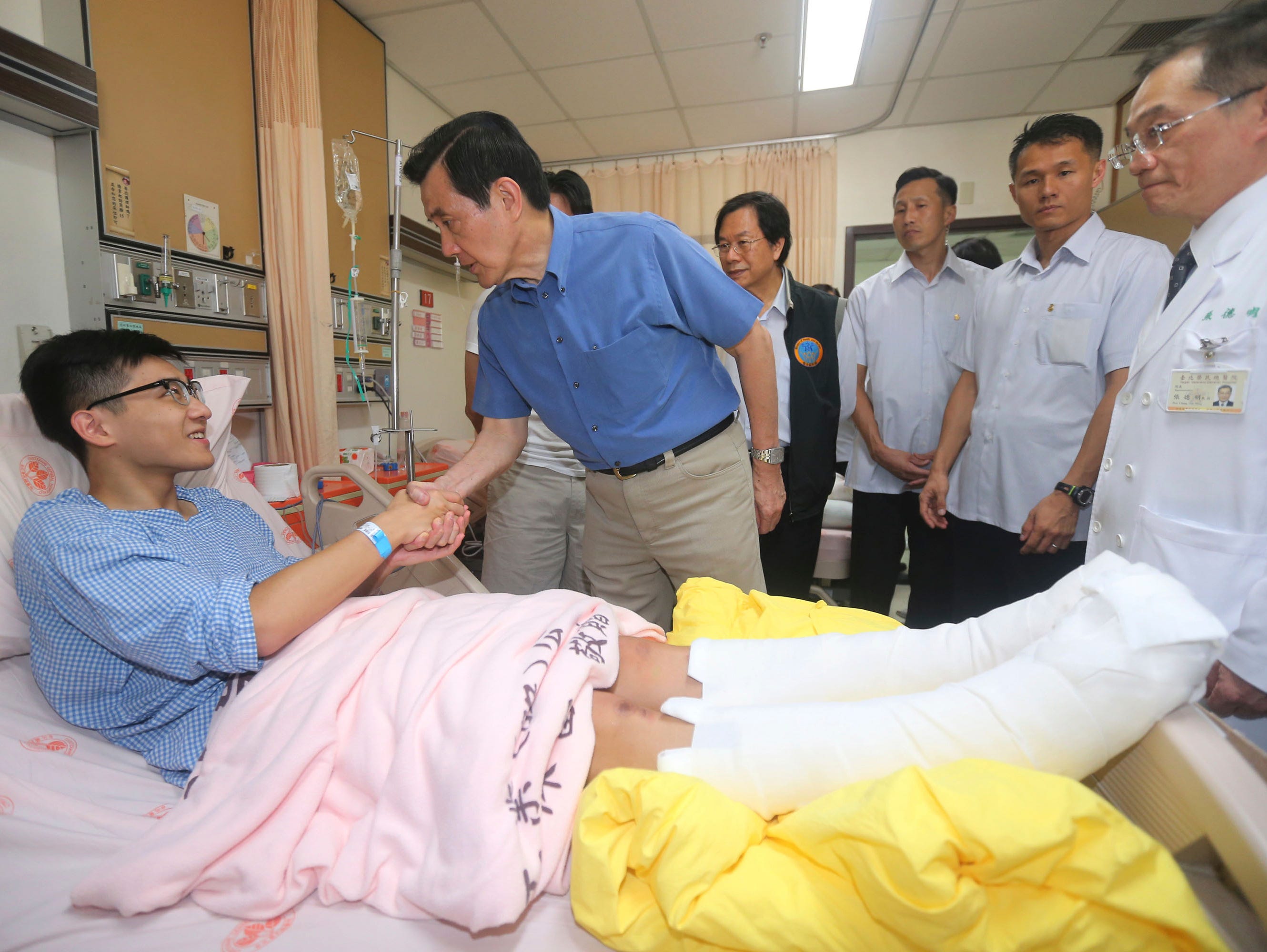 Taiwanese President Ma Ying-jeou shakes hands with a victim injured in an accidental explosion during a music concert, in New Taipei City, Taiwan, Sunday, June 28, 2015.